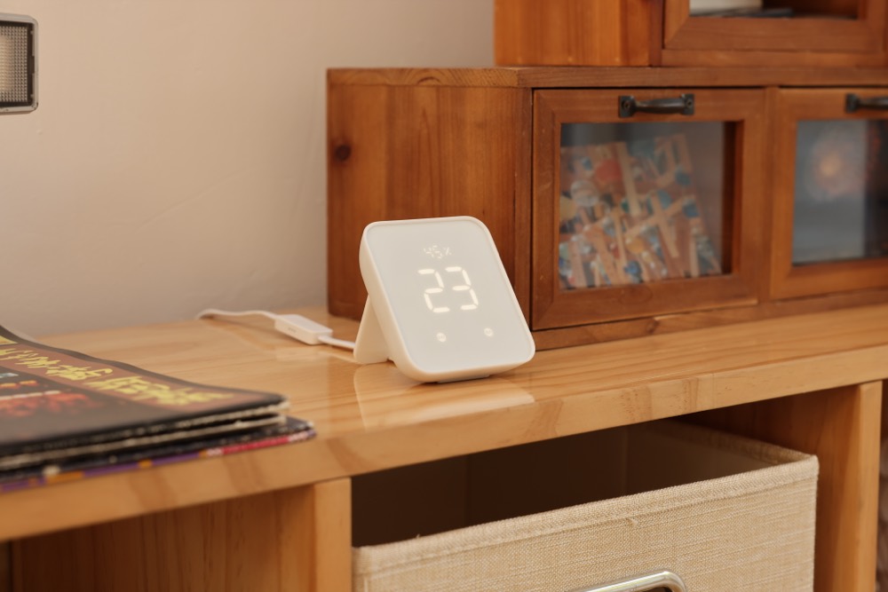 木製のカウンターに置いた SwitchBot ハブ2。スタンド型の本体が室温 23 度を表示している